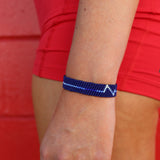 Person wearing a blue beaded bracelet on a red background