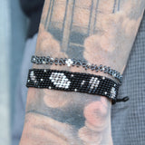 thin and stretchy gray bracelet with silver dots depicting a night sky, with a white star in the center. handmade in Kenya