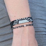 thin dark gray beaded bracelet depicting a large white star in the center and smaller silver stars around it. Handmade in Kenya
