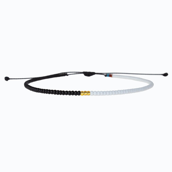 Black and white beaded anklet with gold accents on a white background