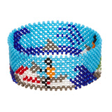 A beaded ArtiKen bracelet, handmade in Kenya, showcasing a day out on the waves, a blue background with dark blue waves and two people on red and green jet skis.