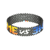 A handmade beaded bracelet from ArtiKen created in Kenya displaying the text Me vs Me in black, orange and blue.