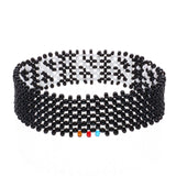 A handmade in Kenya, ArtiKen bracelet displays the zeros of a stop watch in white beads on a black background. 